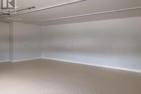Interior view of an empty commercial space with white walls, a light beige floor, and overhead fluorescent lighting. - D4 - 14 Winstar Road, Oro Medonte