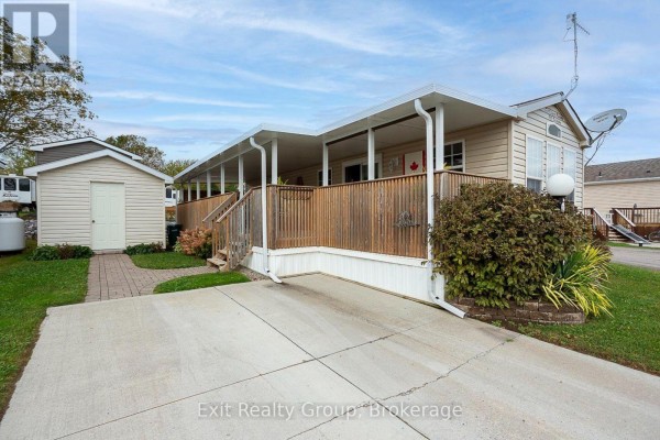 View of a mobile home with a covered deck, wooden railings, and a storage shed. - D7 - 153 County Road 27, Prince Edward County