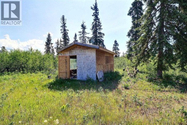 Small shed with wooden structure surrounded by trees and grass. - Dl 1109 Atlin Road, Atlin