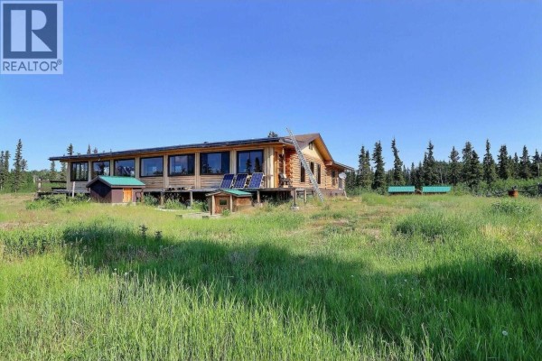 Side view of the house featuring solar panels and a green shed. - Dl 1109 Atlin Road, Atlin