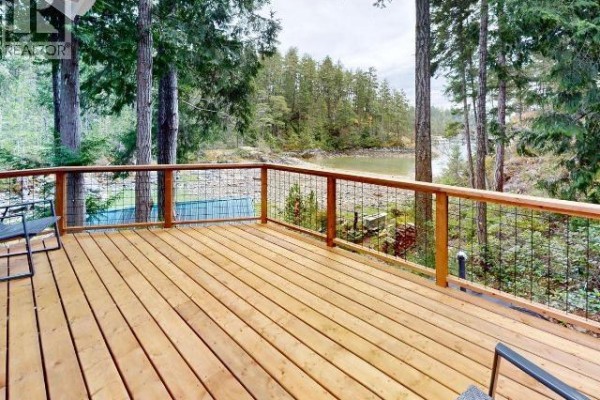 A wooden deck with metal railings overlooks a calm cove surrounded by tall green trees and rocky shores. - Dl4946 Refuge Cove, Remote Areas