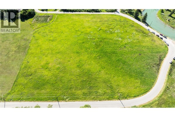 Aerial view of a large, cleared, green lot with a curved road and river. - Downey Road Lot# Lot 26, Fairmont Hot Springs