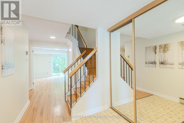 Interior foyer and staircase with wood railing, mirrored closet, and hallway to living area. - E - 6 Millrise Lane, Ottawa