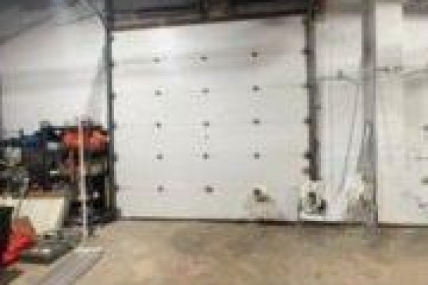 Large white overhead garage door inside a commercial building with industrial shelving. - E - 866 Phillip Street, Sarnia