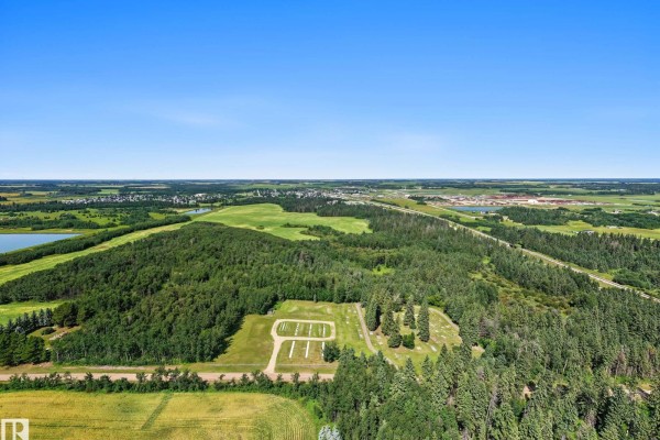 Aerial perspective of a cemetery plot surrounded by trees, with fields and a town in the background. - E-29-47-24-4 County Of Wetaskiwin, Rural Wetaskiwin County