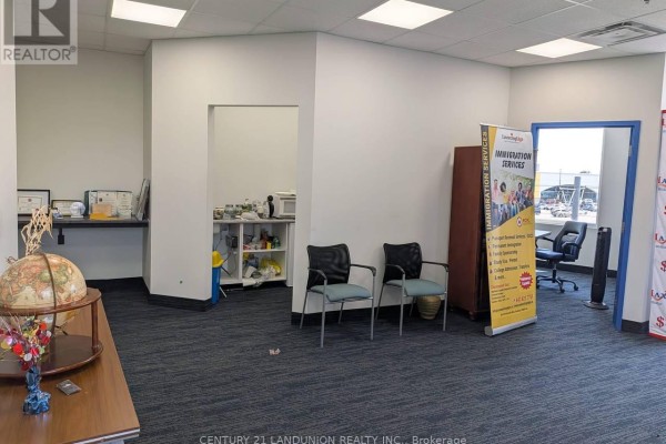 Waiting area with chairs, a desk, and promotional banners for immigration services. - E204 - 6100 Finch Avenue W, Toronto