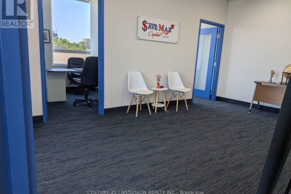 Reception area with modern white chairs, a small table, and blue-trimmed doorways. - E204 - 6100 Finch Avenue W, Toronto