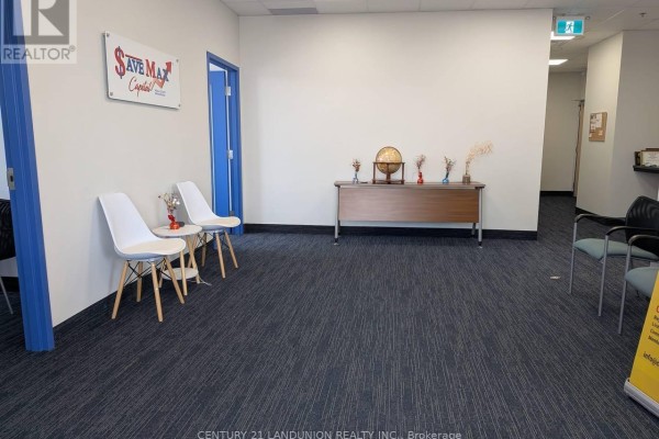 Office waiting area with a wooden desk displaying a globe, and seating. - E204 - 6100 Finch Avenue W, Toronto