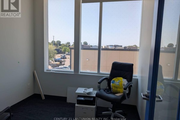 Office interior with a large window, black office chair, and printer on a filing cabinet. - E204 - 6100 Finch Avenue W, Toronto