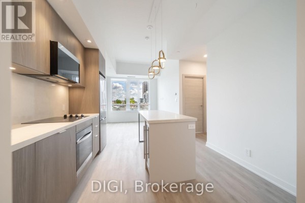 Kitchen with light wood cabinets, stainless steel appliances, island, and window view. - E438 - 485 Perth Avenue, Toronto