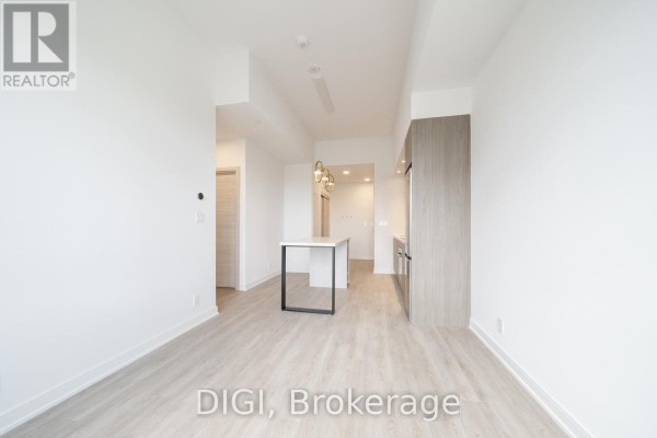 Spacious living area with light wood floors and view of the kitchen. - E438 - 485 Perth Avenue, Toronto