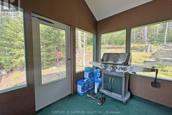 Screened-in porch with a stainless steel grill, water jugs, and a door. - Eagles Nest, Thunder Bay Remote Area