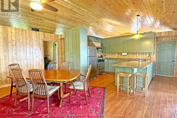 Dining area and kitchen with wood paneled walls, green cabinets, and island. - Eagles Nest, Thunder Bay Remote Area