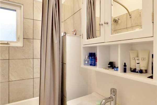 Bathroom with tiled walls, shower/tub combo, and built-in shelving for toiletries. - East #1 - 122 Forsyth Street, Sarnia