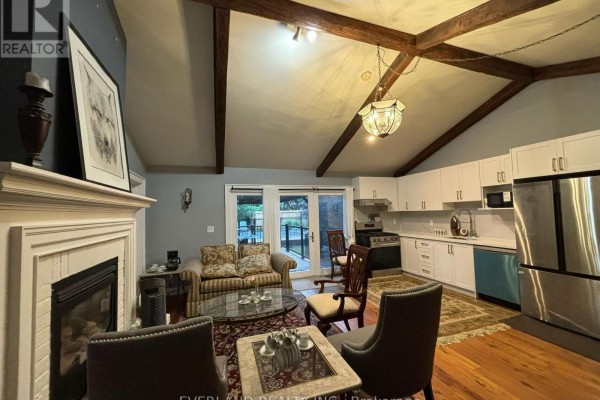 Living area and kitchen with white cabinets, stainless steel appliances, and a fireplace. - Ensuite Room - 3369 St Paul Avenue, Niagara Falls