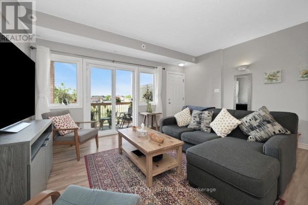 Living room with a sectional sofa, coffee table, large windows, and a balcony view. - F - 1105 Stittsville Main Street, Ottawa