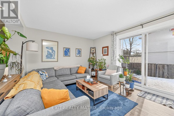 Living room with grey sectional sofa, coffee table, and a view to the backyard. - F - 1777 Lamoureux Drive, Ottawa