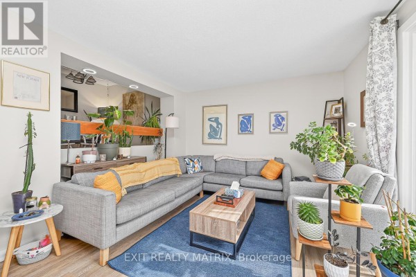 Living room with a large grey sectional sofa, fireplace, and a view to the backyard. - F - 1777 Lamoureux Drive, Ottawa