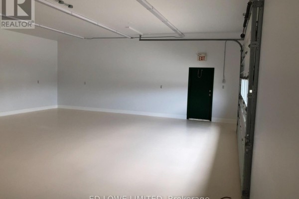 Commercial space with overhead door, dark green exit door, and white walls. - F1 & F2 - 14 Winstar Road, Oro Medonte