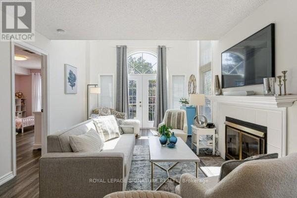 Living room featuring a grey sofa, fireplace, and French doors leading outdoors. - F17 - 1667 Nash Road, Clarington
