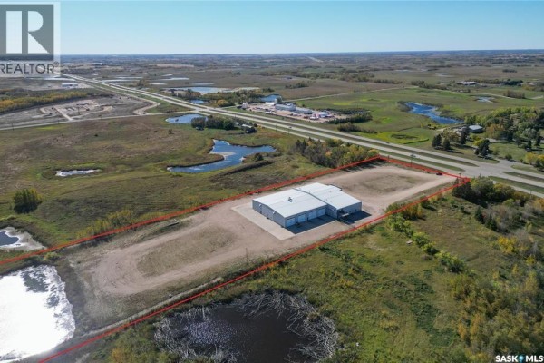 Wide aerial view showing a commercial building surrounded by wetlands and a highway in the distance. - Farm World Prince Albert, Prince Albert Rm No  461