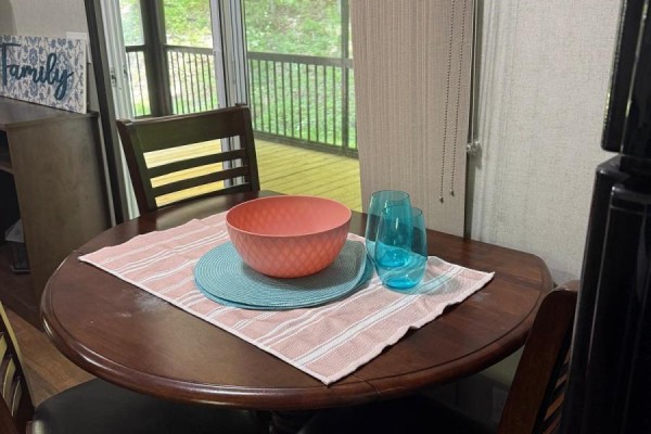 Round wooden dining table with two chairs and a pink and white striped placemat. - Fnc426 - 1047 Bonnie Lake Camp Road, Bracebridge