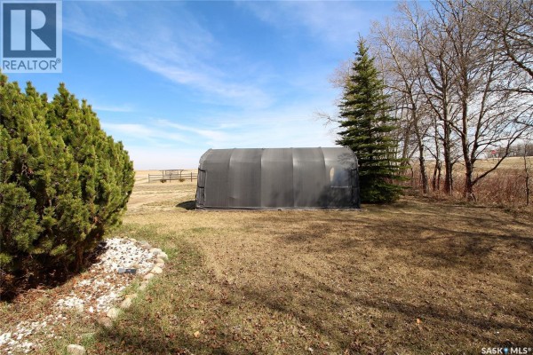 A grey hoop building sits on a grassy lawn with a large evergreen tree to its right. - Frank Acreage, Wawken Rm No  93