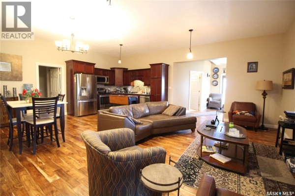 An open-concept living room and kitchen with a large sectional sofa, dining table, and wood floors. - Frank Acreage, Wawken Rm No  93