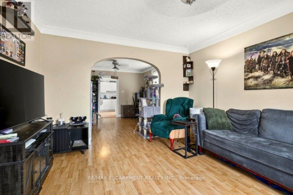 Living room with a sofa, armchair, cat tree, and an archway leading to another room. - Front - 66 Queen Street S, Thorold
