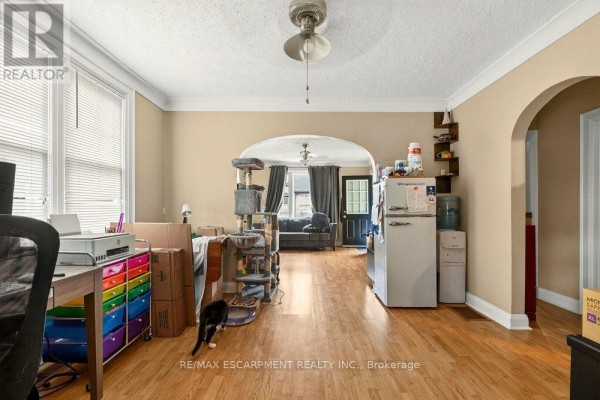 View from living room showing archway to another room with a refrigerator and window. - Front - 66 Queen Street S, Thorold