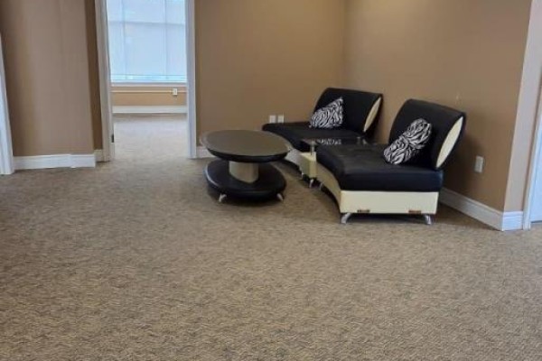 Interior waiting area with two black couches, zebra print cushions, and a coffee table. - G - T4 - 400 Dundas Street, Whitby