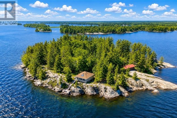Expansive view of a calm lake from a rocky outcrop with trees and shoreline in the distance. - G2 West Bay Island, Monetville