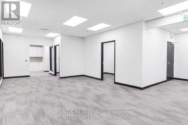 Hallway view of an empty office with black-trimmed doorways and a small kitchenette area. - G206& 207 - 450 Hespeler Road, Cambridge