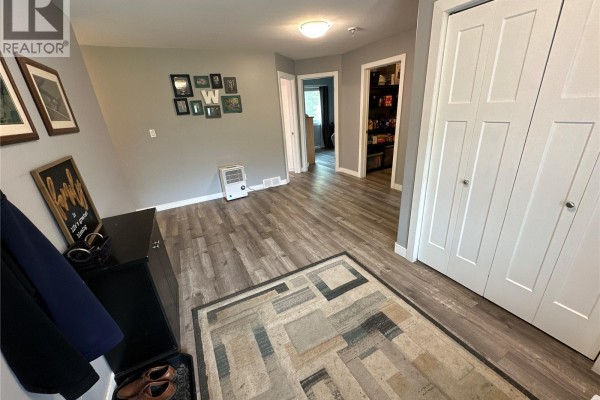 Entranceway with grey walls, wood-look flooring, and double bi-fold closet doors. - Gabriel Bridge Acreage, Fish Creek Rm No  402