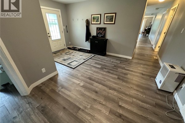 Front entry with a glass door, grey walls, wood-look flooring, and a rug. - Gabriel Bridge Acreage, Fish Creek Rm No  402