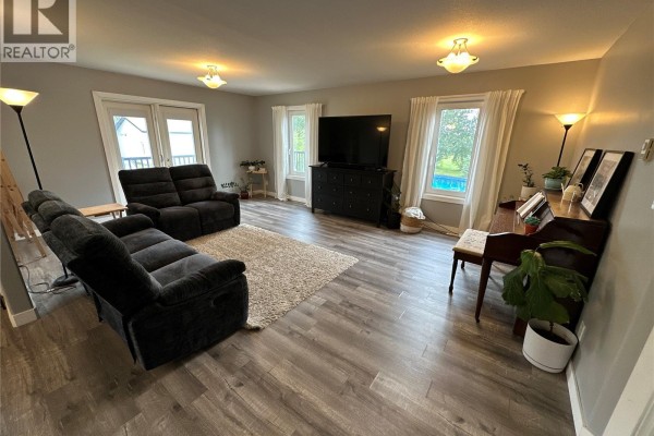 Living room with grey walls, dark reclining sofas, a television, and a piano. - Gabriel Bridge Acreage, Fish Creek Rm No  402