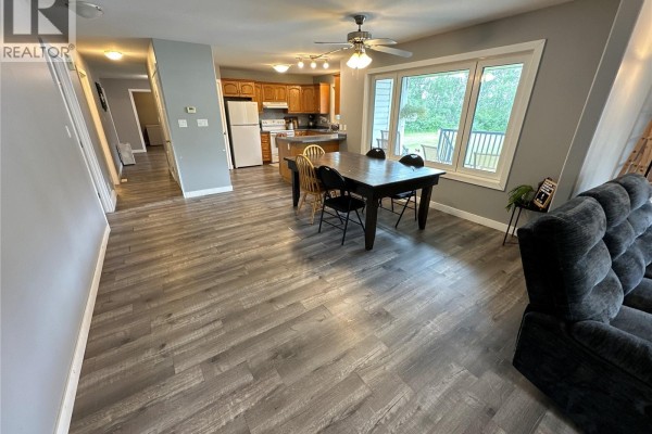 Open concept living and dining area with a kitchen and large window overlooking the yard. - Gabriel Bridge Acreage, Fish Creek Rm No  402