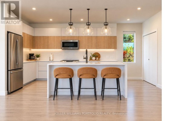 Modern kitchen with white countertops, light wood cabinetry, stainless steel appliances, and a large island. - Garden Residence - Sugar Ridge Condos Valley Road, Antigua