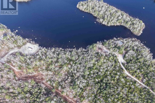 Aerial view of a wooded shoreline on a dark lake with a small island in the distance. - Granite Ridge Road, Birchtown