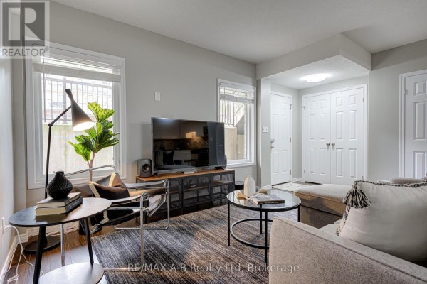 Living room featuring a sectional sofa, coffee table, and a television console against a light grey wall. - H - 242 Rachel Crescent, Kitchener