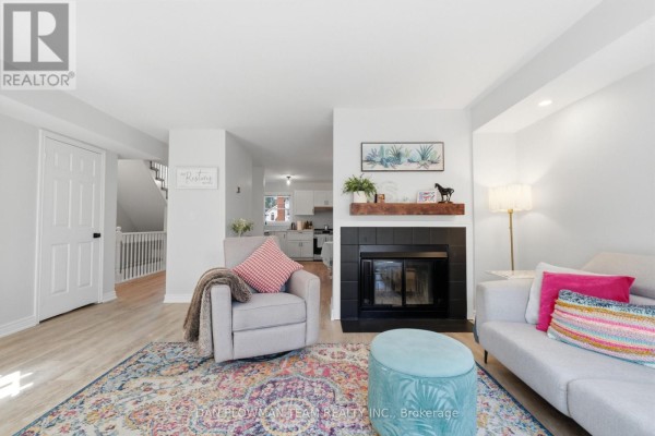 Living room fireplace with stone surround, sectional sofa, and armchair in front of it. - H11 - 76 - 1661 Nash Road, Clarington