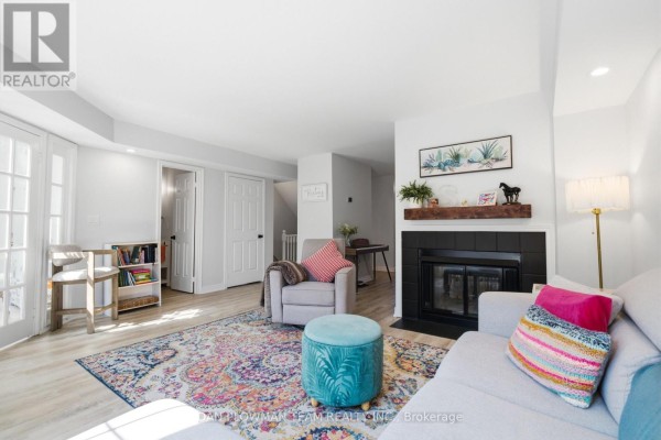 Living room fireplace, seating area, and doors to the backyard. - H11 - 76 - 1661 Nash Road, Clarington