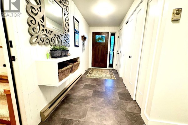 Interior hallway with dark gray tile flooring, white closet doors, and a door to the outside. - Hague Acreage, Rosthern Rm No  403