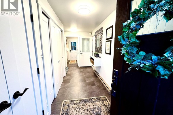 Entryway with dark wooden door, decorative mirror, white paneled walls, and light gray tile flooring. - Hague Acreage, Rosthern Rm No  403