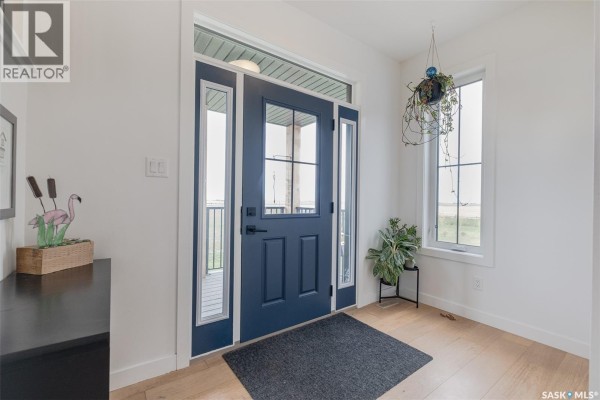 Interior view of the home's blue front door with sidelight windows and a light wood floor. - Hayter Acreage, Dufferin Rm No  190