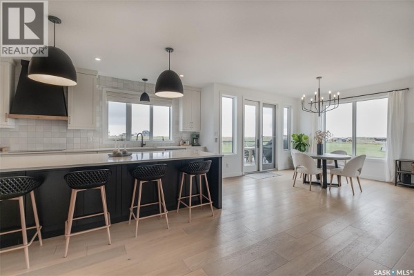Open concept kitchen and dining area with a large island, white cabinets, and pendant lights. - Hayter Acreage, Dufferin Rm No  190