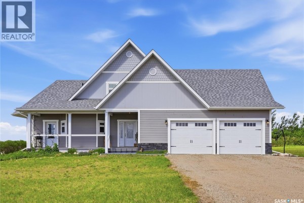 Front view of a two-story grey house with a white front door and three garage doors. - Highway 15 Outlook Acreage, Rudy Rm No  284