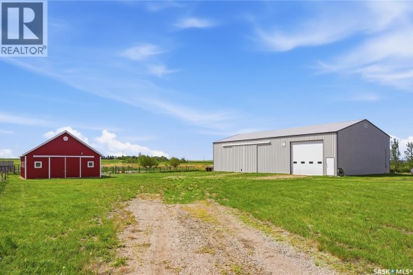 A red barn and a large grey metal workshop with a large garage door are shown. - Highway 15 Outlook Acreage, Rudy Rm No  284