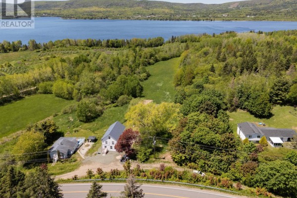 Aerial view of a white house and neighboring properties with a blue lake and forested hills. - Highway 201, Moschelle