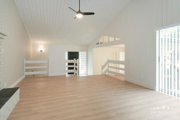 Living room with vaulted wood-paneled ceiling, white brick fireplace, and view of staircase. - House 12687 23 Avenue, White Rock